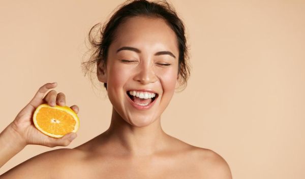 Frau mit halber Orange in der Hand