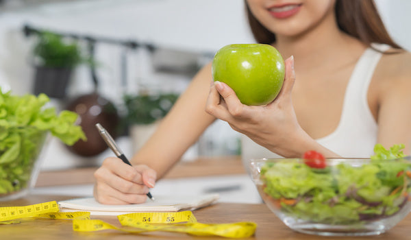 Frau mit Apfel Maßband und Salat