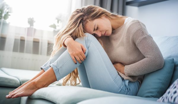 Frau mit PMS Beschwerden auf der Couch