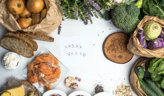 Verschiedene Lebensmitte um einen Zettel mit der Aufschrift Amino Acid